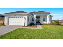 Beautiful single-story home with a white exterior, well-kept lawn, and a two-car garage at 200 Snowy Orchid Way, Lake Alfred, FL 33850