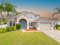 Charming two-story home featuring a lush front yard, a blue front door, and a spacious three-car garage at 2333 Pesaro Cir, Ocoee, FL 34761