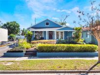 Charming blue home featuring manicured front yard with lush landscaping and inviting curb appeal at 434 E Harding St, Orlando, FL 32806