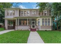 Charming two-story home with a landscaped front yard, inviting screened porch, and convenient covered parking at 803 E Harwood St, Orlando, FL 32803