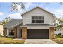 Two-story home showcasing neutral siding, brick accents, attached garage, and manicured front lawn at 1063 Eagles Forrest, Apopka, FL 32712