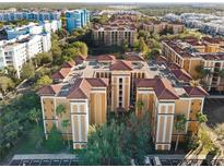 An aerial view of a multi-Gathering complex with a red tile roof surrounded by green trees and other buildings at 12521 Floridays Resort Dr # 307F, Orlando, FL 32821
