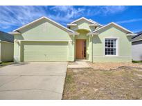 Inviting one-story home with a two-car garage, manicured lawn, and a light green exterior at 326 Cotswold Cir, Davenport, FL 33837