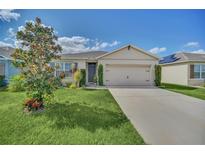 Charming single Gathering home featuring a well-manicured lawn, neutral color palette, and an attached two car garage at 3308 Country Walk Club Cir, Winter Haven, FL 33881