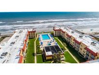 Aerial view shows the community pool, ocean access and meticulously kept landscaping at 3801 S Atlantic Ave # 105, New Smyrna Beach, FL 32169