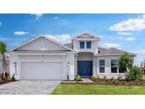 Beautiful, single-story home featuring a 2-car garage, blue front door, manicured lawn, and thoughtfully designed landscaping at 5641 Nevis Ter, Kissimmee, FL 34758