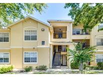 Charming condo exterior featuring a stairway and small balconies framed by lush greenery at 2624 Robert Trent Jones Dr # 633, Orlando, FL 32835