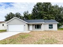 Newly renovated single-story home featuring a fresh gray exterior, a two-car garage, and a well-manicured front yard at 1 Pine Radial Trl, Ocala, FL 34472