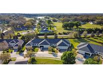 An aerial view of homes next to a golf course and a small lake in a sunny and green community at 1024 Green Gate Blvd, Groveland, FL 34736