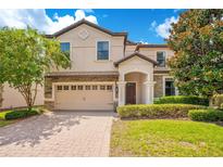 Charming two-story home featuring a brick driveway, two-car garage, and lush landscaping at 1445 Rolling Fairway Dr, Davenport, FL 33896