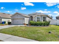 Charming single-story home with manicured lawn, gray exterior, and attached two-car garage at 3086 Brenton Manor Loop, Winter Haven, FL 33881