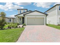 Charming home featuring a two-car garage, brick driveway, and beautifully landscaped front yard at 3213 Viceroy Ct, Poinciana, FL 34759
