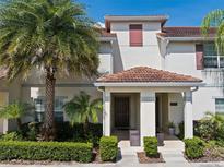 Inviting two-story townhome with a tile roof, lush landscaping, and a charming covered entryway at 4895 Clock Tower Dr, Kissimmee, FL 34746