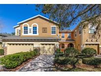 Charming two-story townhome featuring a two-car garage, beautifully landscaped yard, and colorful exterior at 5252 Hidden Cypress Ln, Oviedo, FL 32765