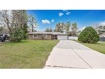 Charming single-story home featuring a long driveway and attached two-car garage at 5410 S Pine Hill Cir, Orlando, FL 32808
