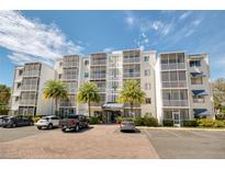 Condo building featuring a white facade, multiple balconies, and well-maintained landscaping with palm trees at 1100 Delaney Ave # F409, Orlando, FL 32806