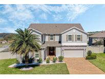 Beautiful two-story home featuring a brick driveway, stone accents, and a lush, green front yard with a palm tree at 1880 Bonser Rd, Minneola, FL 34715