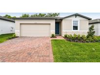 Charming one-story home featuring a brick driveway, attached garage, and beautifully landscaped front yard at 2310 White Tail St, Davenport, FL 33837