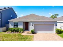 Charming single Gathering home featuring a brick walkway, well-maintained lawn, and a two-car garage at 249 Hamlet Loop, Davenport, FL 33837