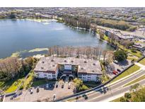 Stunning aerial view of lakeside apartments, showcasing the building, surrounding trees, and ample parking at 4575 S Texas Ave # 205, Orlando, FL 32839