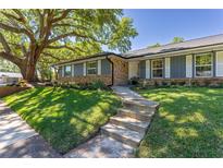 Charming single-story home with blue painted siding and brick accents, and mature tree in a well-landscaped front yard at 7614 Lake Dr, Belle Isle, FL 32809
