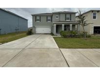 Charming two-story home with a large driveway, attached garage, and covered porch at 124 Sofia Ln, Lake Alfred, FL 33850
