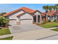 Beautiful single-story home featuring a terra cotta roof, three-car garage, and lush landscaping at 2541 Shoal Bass Way, Kissimmee, FL 34746