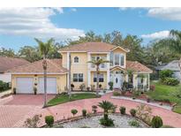 Beautiful two-story home featuring a Spanish tile roof, lush landscaping, and a circular driveway at 2747 Kissimmee Bay Cir, Kissimmee, FL 34744