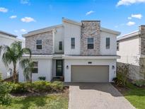 Modern two-story home featuring stone accents, a two-car garage, and a well-maintained front yard at 8816 Cruden Bay Ct, Davenport, FL 33896