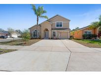 Two-story home featuring neutral stucco, an attached garage, and a well-manicured lawn with palm tree at 877 Scrub Jay Way, Davenport, FL 33896