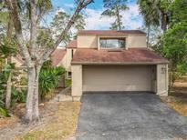 Beige two-story home featuring an attached two-car garage, asphalt driveway, and mature landscaping at 117 Starling Ln, Longwood, FL 32779