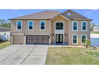 Charming two-story home featuring an attached garage, well-manicured lawn, and a welcoming double-door entrance at 1705 Ridgemoor Dr, Mascotte, FL 34753