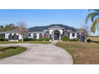 Stunning single-story home featuring modern architectural style, circular driveway, solar panels, and lush landscaping at 17117 Heartwood Loop, Winter Garden, FL 34787