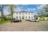 Stunning white two-story home with a circular driveway and two luxury sports cars at 1943 Wingfield Dr, Longwood, FL 32779