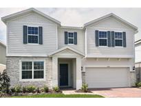 Charming two-story home with gray stone accents, a two-car garage, and a neatly landscaped front yard at 1988 Iorio Dr, St Cloud, FL 34771
