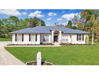 Charming home featuring a manicured lawn, elegant arched entryway and beautiful landscaping at 2606 Woodwind Hills Ln, Lakeland, FL 33812