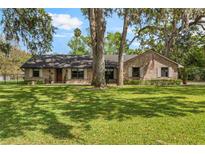 Charming brick home featuring a well-manicured lawn and mature trees offering shade at 598 Palm Dr, Oviedo, FL 32765