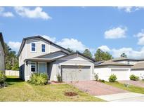 Charming two-story home featuring gray siding, a brick driveway, and a light blue front door at 869 Rivers Crossing St, Clermont, FL 34714