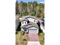 Charming two-story home with a well-manicured lawn and brick driveway, complemented by mature trees at 869 Rivers Crossing St, Clermont, FL 34714