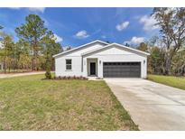Charming one-story home with a well-manicured lawn and a two-car garage on a sunny day at 12639 Sw 78Th Pl, Dunnellon, FL 34432