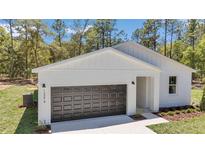 Charming white home showcasing modern architecture, a dark garage door and well-maintained landscaping at 13274 Sw 82Nd Ln, Dunnellon, FL 34432