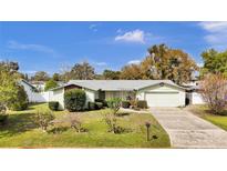 Inviting single-story home featuring a well-manicured lawn, mature trees, and an attached two car garage at 2231 Louise St, Kissimmee, FL 34741