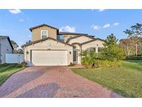 Inviting two-story home with a manicured lawn, brick driveway, and attached two-car garage at 2940 Scarlett Dr, St Cloud, FL 34772