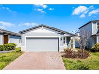Charming one-story home featuring a two-car garage and manicured front yard with a brick paver driveway at 29400 Caspian St, Leesburg, FL 34748