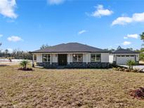 Charming single-story home featuring a modern exterior, stone accents, and a detached garage at 31905 Larkspur Ave, Eustis, FL 32736