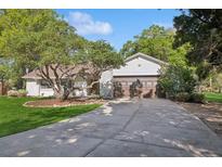 Charming single-story home with a stone facade and a well-maintained lawn and a large driveway leading to an attached garage at 600 Tuskawilla Point Ln, Winter Springs, FL 32708