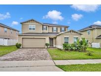 Two-story home featuring a brick driveway, a two-car garage and manicured landscaping at 638 Ogelthorpe Dr, Davenport, FL 33897