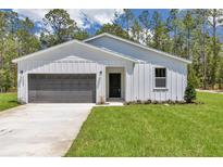 Charming single-story home with a well-manicured lawn and a gray garage door, surrounded by lush trees at 7007 Sw 131St Ave, Ocala, FL 34481