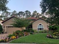 Charming home featuring a beautifully landscaped front yard with vibrant flowers and lush green grass at 9346 San Jose Blvd, Howey In The Hills, FL 34737