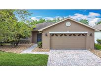 Charming single-story home with a brick driveway, mature landscaping, and a two-car garage at 124 Meridian Ave, Kissimmee, FL 34759